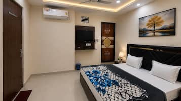 A bedroom with a bed, a television, a ceiling fan, and a painting on the wall.
