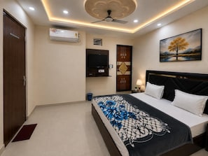Ein Schlafzimmer mit einem Bett, einem Fernseher, einem Deckenventilator und einem Gemälde an der Wand.