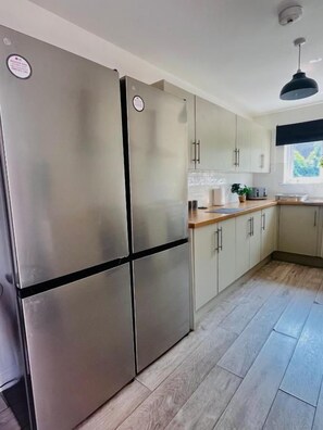 Una cocina moderna con electrodomésticos de acero inoxidable, armarios de tonos claros y encimera de madera.
