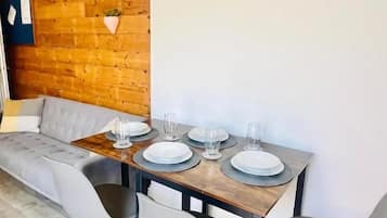 Un comedor con pared de madera, un reloj redondo y un sofá.