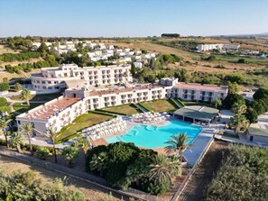 Un complex turístic amb diversos edificis, una piscina i zones ajardinades.