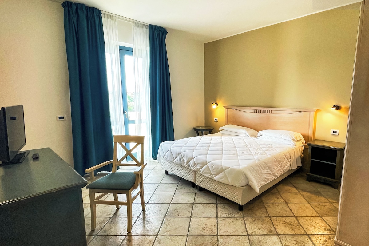 Una habitació d'hotel amb un llit, un escriptori, una cadira i una televisió.
