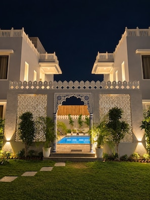 A building with a central entrance, a pool, and a well-maintained lawn. - The OG Stays (Jaipur)