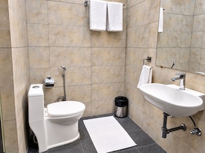 A modern bathroom with a toilet, bidet, sink, and a mirror. - The OG Stays (Jaipur)