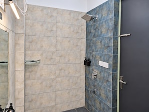 Un baño con ducha, espejo y artículos de aseo.