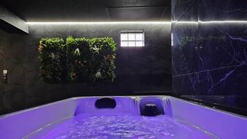 A spa room with a water feature, a window, and a wall with greenery.
