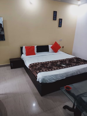 Een hotelkamer met een bed, nachtkastje, tafel en een tv aan de muur.