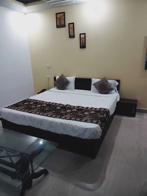 Een hotelkamer met een bed, nachtkastje en foto's aan de wand.