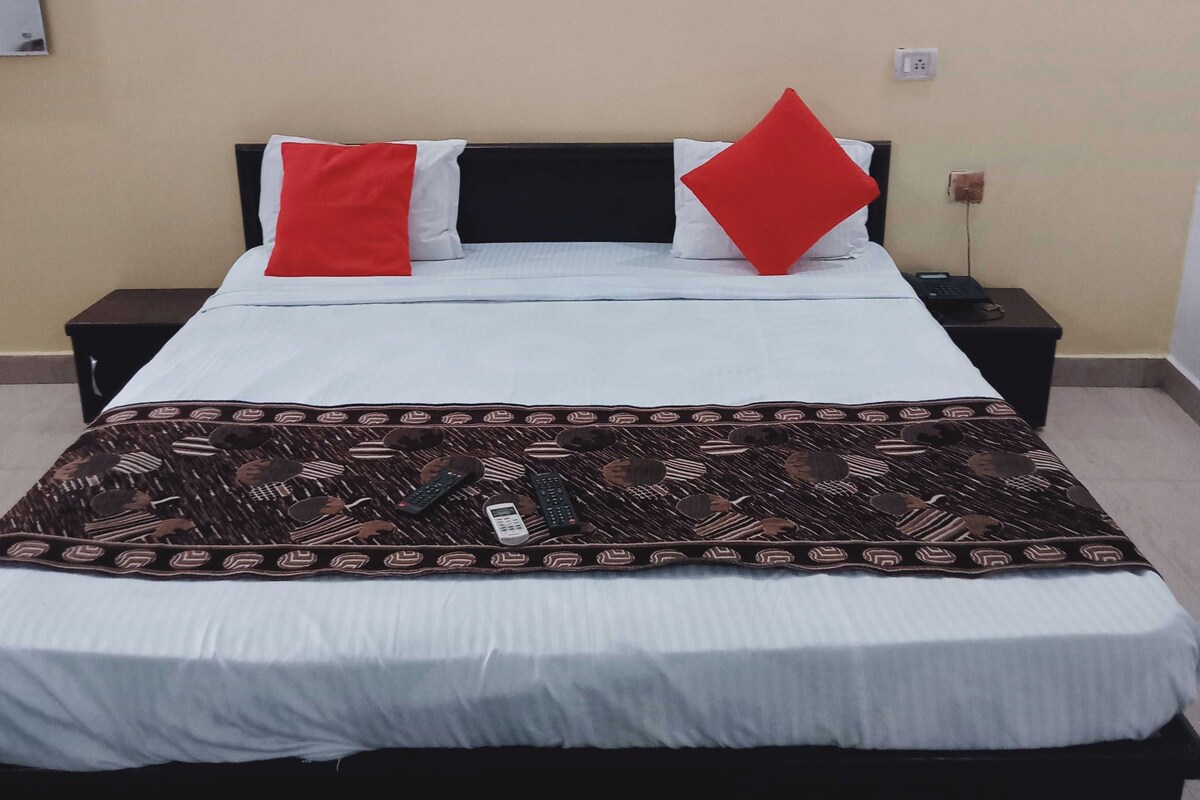 A bed with a patterned bedspread, two nightstands, and a wall with two framed pictures.