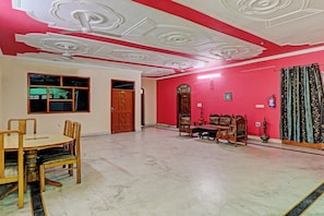 A room with a dining table, chairs, a ceiling fan, and a traditional sofa set. - Hotel O Shiva Grand (Lucknow)