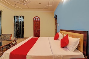A hotel room with a bed, a wooden headboard, a red and white bedspread, and a wooden chair. - Hotel O Shiva Grand (Lucknow)