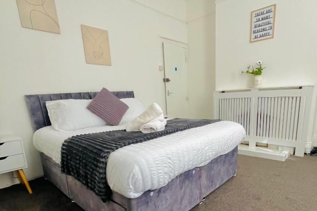 Een slaapkamer met een bed, een witte radiator en kunst aan de muur.