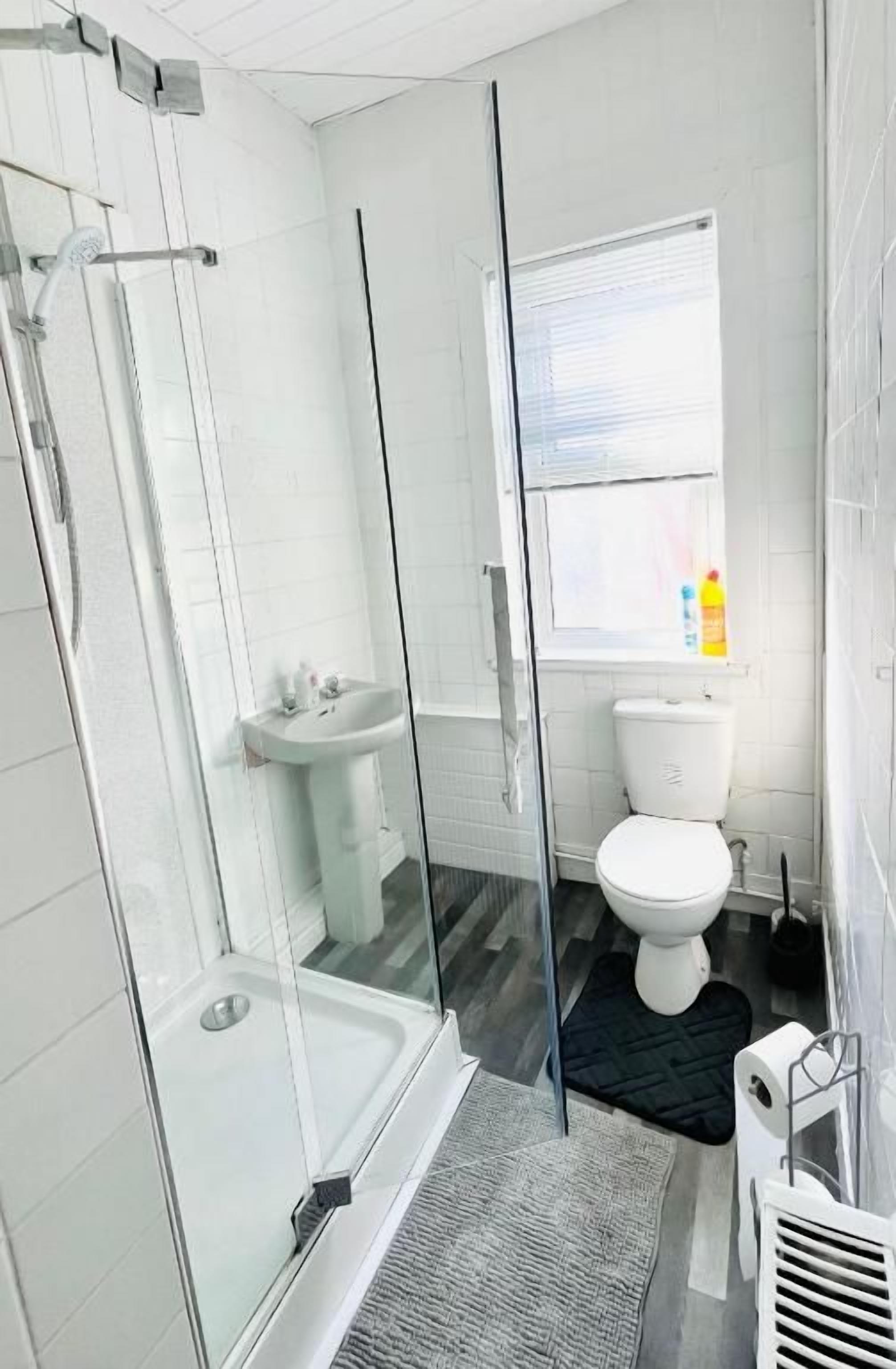 Un baño con cabina de ducha de vidrio, lavamanos blanco y retrete.