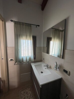 A bathroom with a white sink, a mirror, and a shower area. - Agriturismo Bed Breakfast Tanca Taroni (Sardegna)