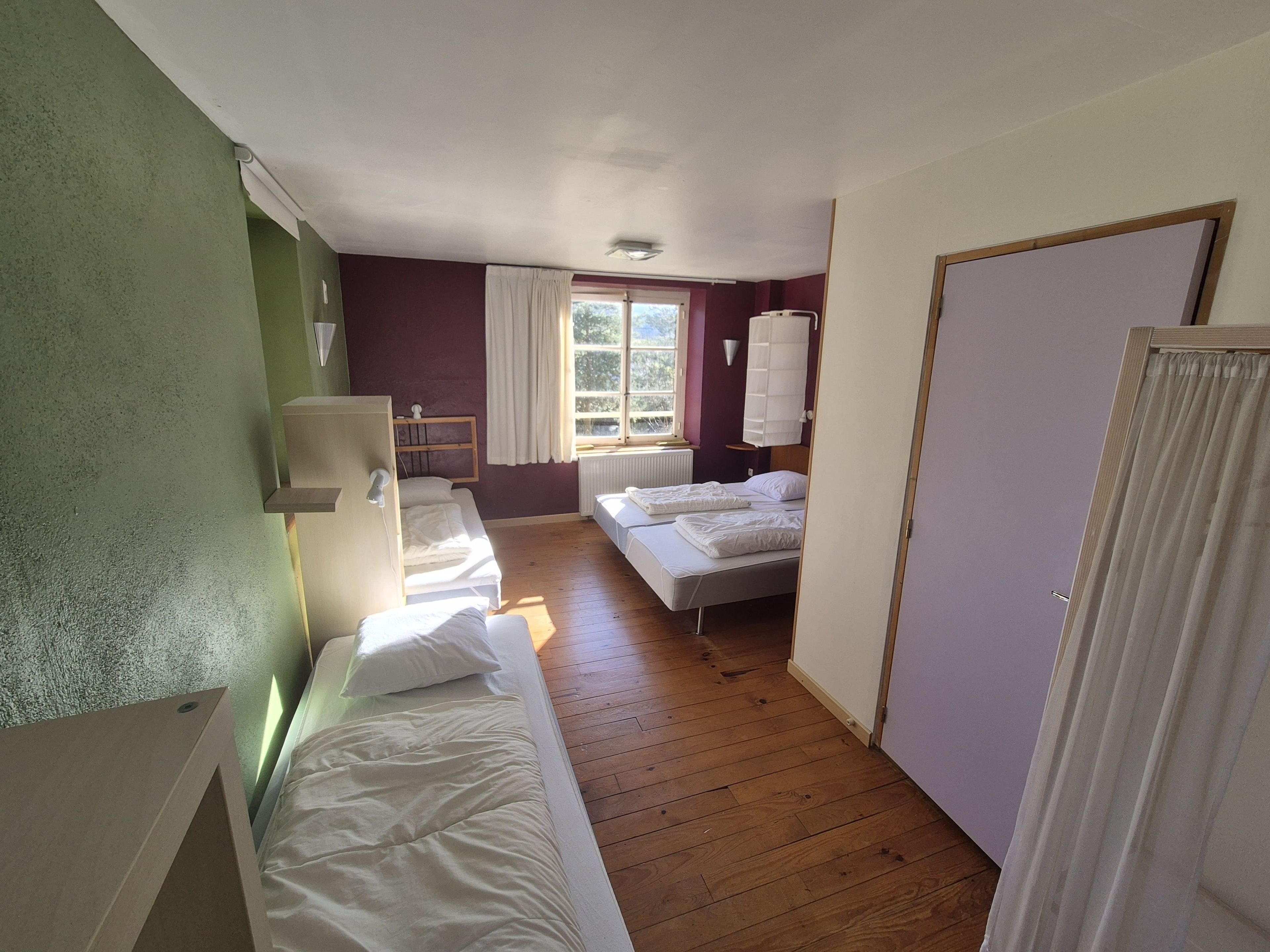 A bedroom with two beds, a window, and a radiator.