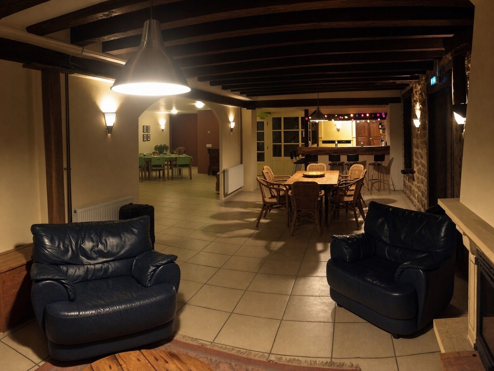 Un rincón comedor acogedor con mesa y sillas de madera, un sofá de cuero negro y una lámpara colgante.