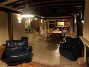 A cozy dining area with a wooden table and chairs, a black leather sofa, and a hanging light fixture.