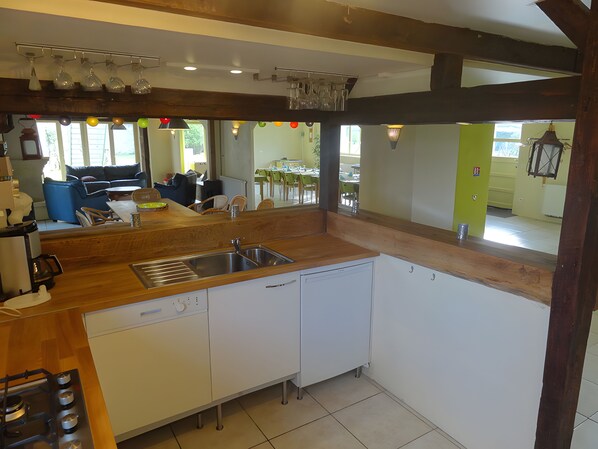 A modern kitchen with a dishwasher, sink, and stove. There is a dining area visible through an open door.