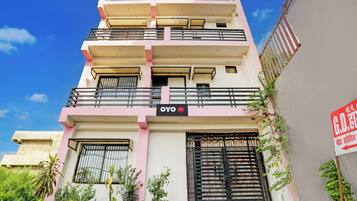 A multi-story hotel with balconies, a sign indicating it is a hotel, and a gated entrance.