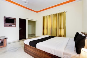 A hotel room with a bed, a television mounted on the wall, and a curtain. - Hotel O Gharaunda (Lucknow)