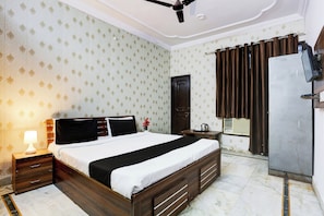 A hotel room with a bed, bedside table, lamp, and a television. - Hotel O Gharaunda (Lucknow)