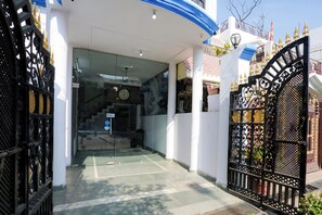 A gated entrance with a clock and a pull sign, leading to a building with a white facade and a blue roof. - Hotel O Gharaunda (Lucknow)