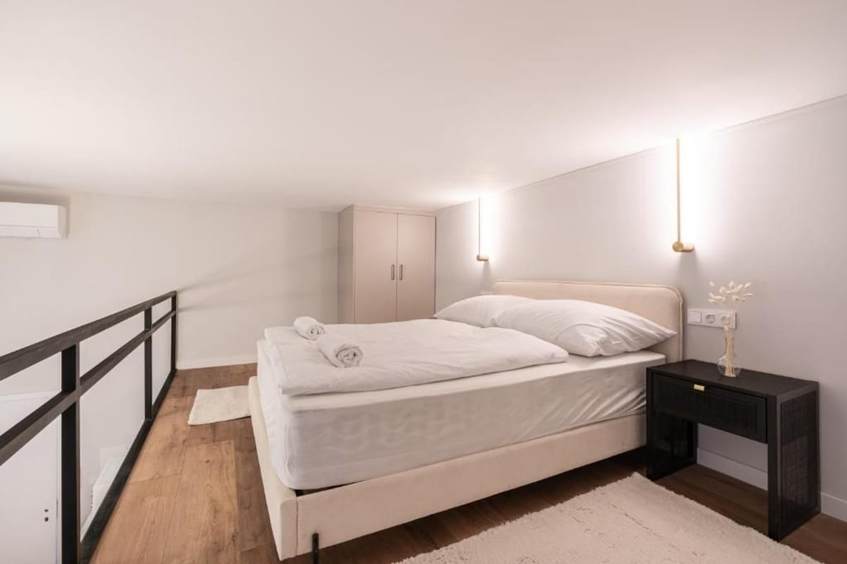 A bedroom with a bed, bedside table, nightstand, and a wardrobe.