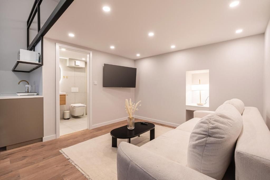 Una sala moderna con un sofá, una mesa de centro y un televisor de pantalla plana montado en la pared.