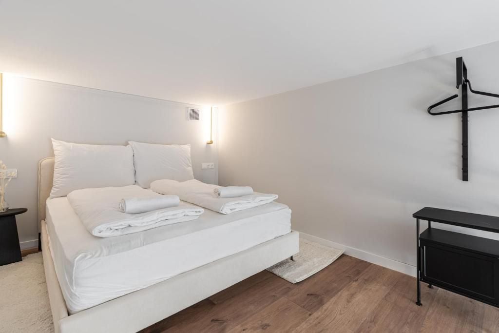 Un dormitorio moderno con una cama grande, lámparas de noche, una mesita de noche negra y un escritorio negro.