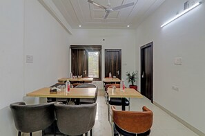 Habitación de hotel con zona de comedor, dos puertas, ventilador de techo y planta en maceta.