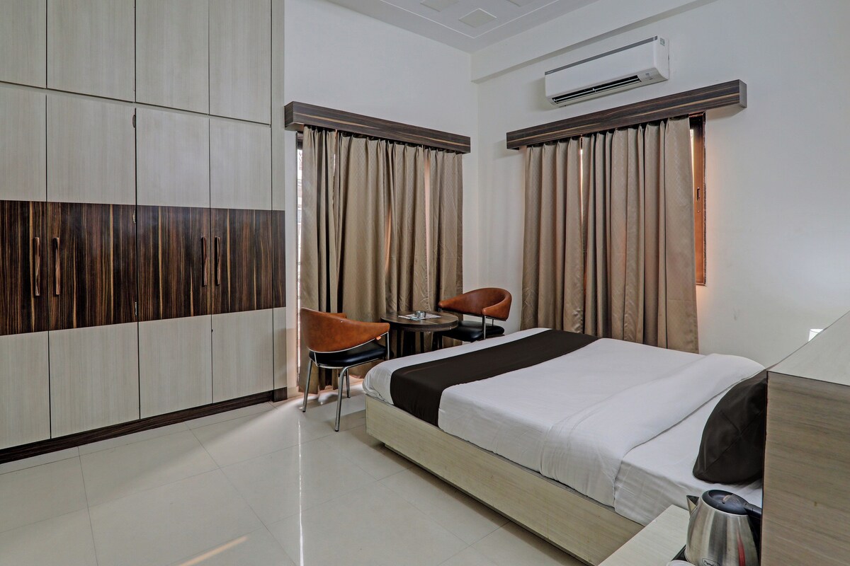 Una habitación de hotel con una cama, una silla, una mesa y un equipo de aire acondicionado.