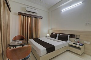 Una habitación de hotel con cama, mesita de noche, silla y aire acondicionado.