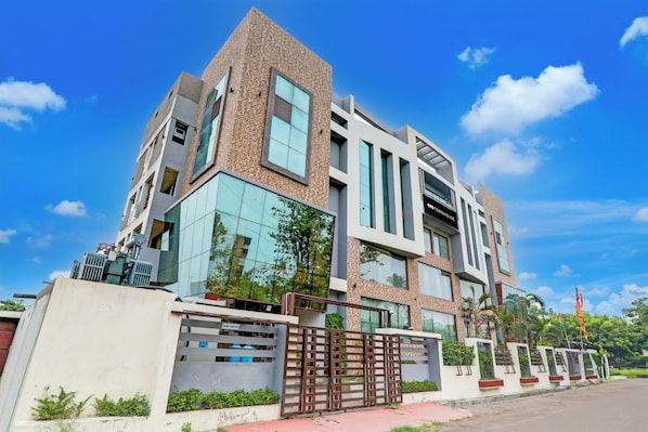 A modern multi-story building with a prominent corner design, large windows, and a gated entrance. - Townhouse Sakura (Lucknow)
