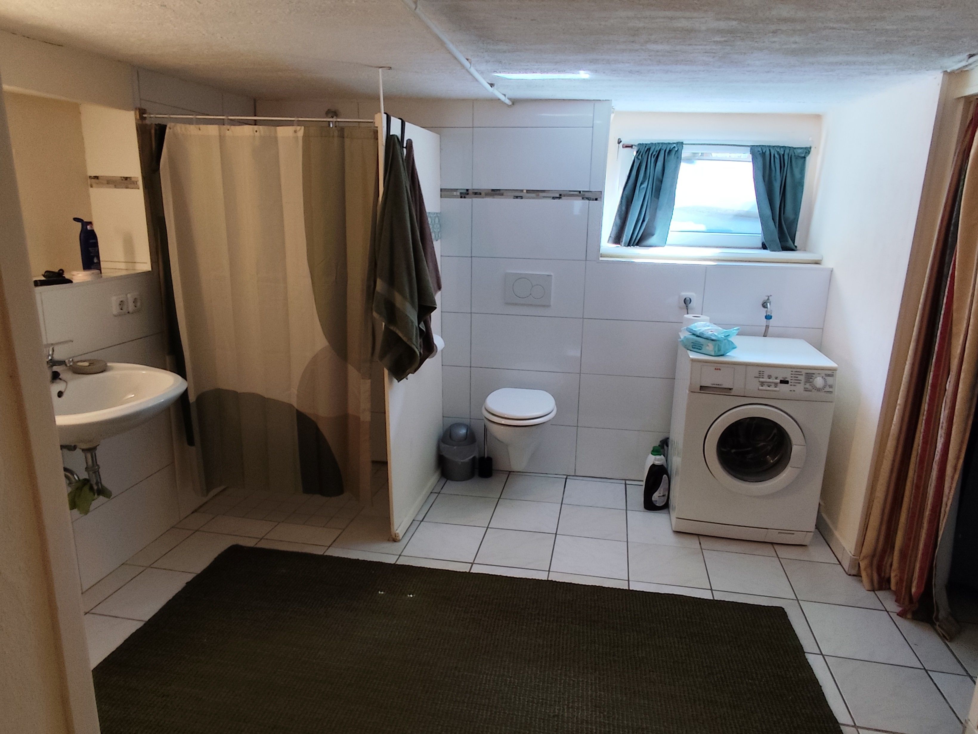 A compact bathroom with a sink, toilet, and washing machine.