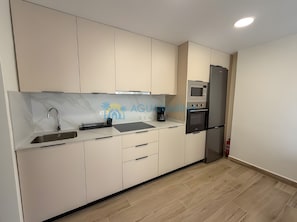 A modern kitchen with a built-in microwave, oven, and stainless steel sink.