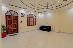 A spacious lobby with a marble floor, a wooden door, a black bench, and a ceiling with recessed lighting and a fan. - Hotel O A B Hotels (Lucknow)