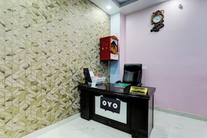 A reception desk with a 'Reception' sign, a computer, a printer, and a decorative clock on the wall. - Hotel O A B Hotels (Lucknow)