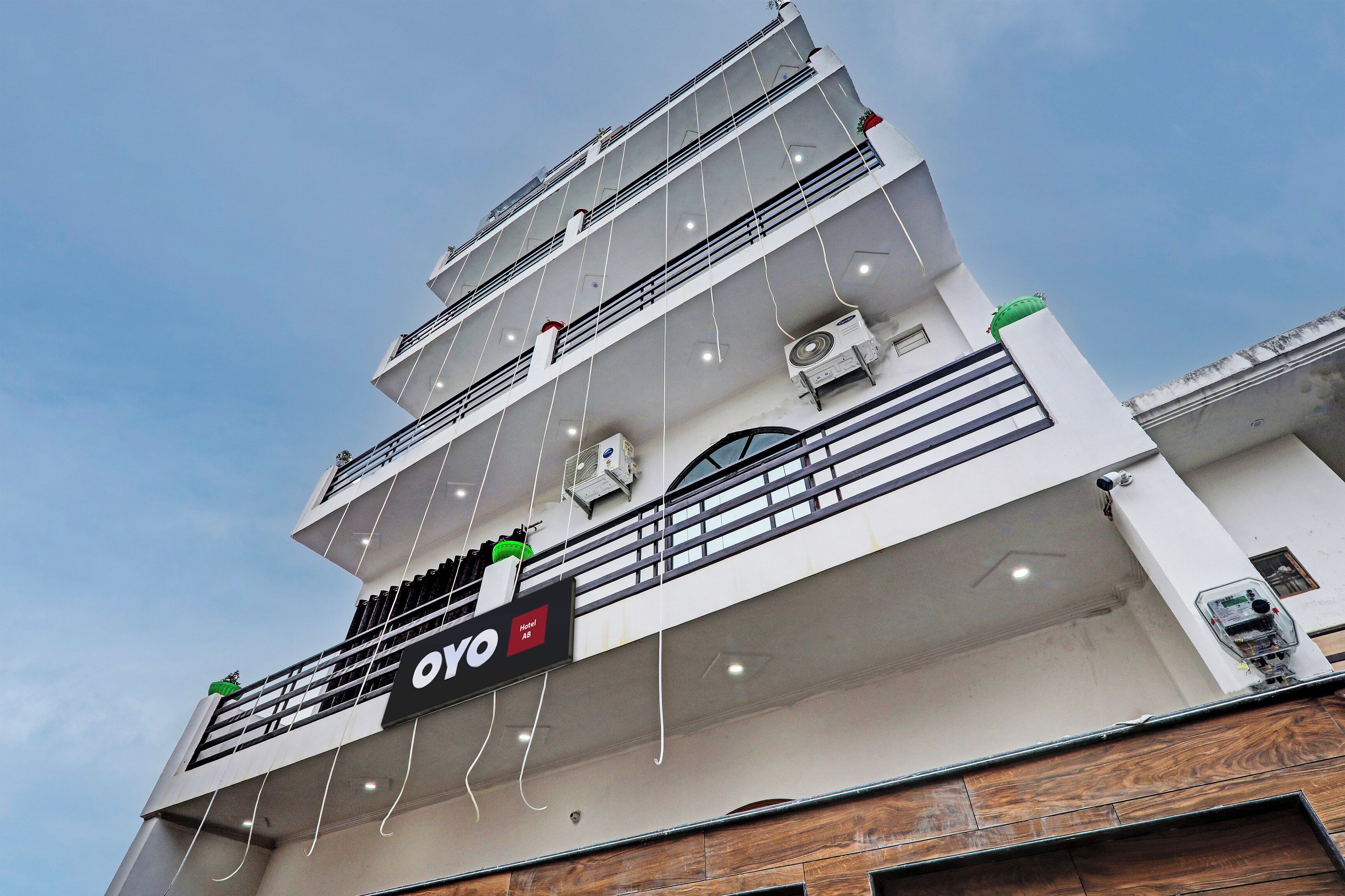 Un hotel de varios pisos con balcones, unidades de aire acondicionado y un letrero que dice 'Hotel AB'.
