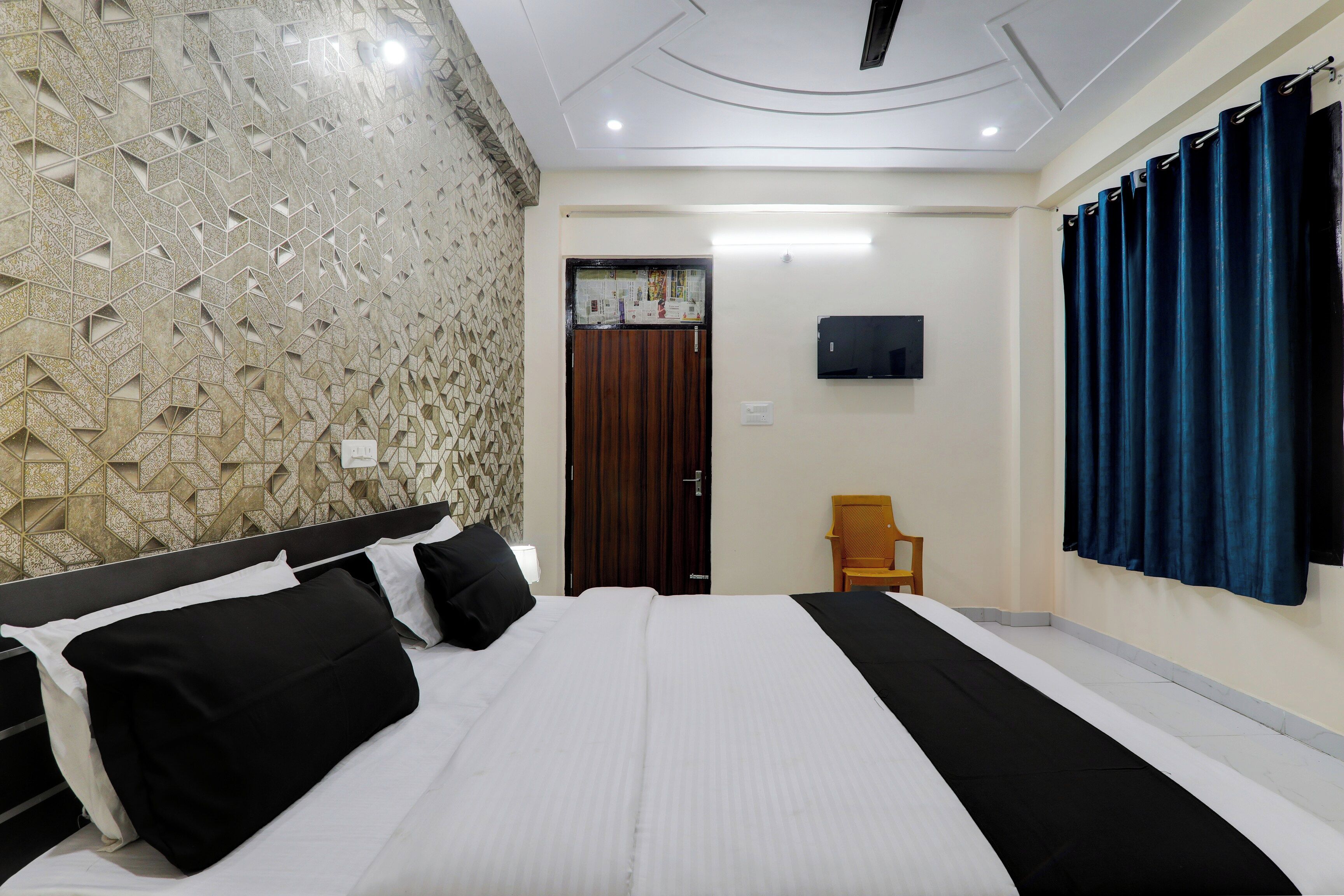 Una habitación de hotel con una cama, televisor, puerta de madera y una silla.
