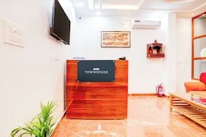 A reception desk with a sign reading 'OYO TOWNHOUSE' in a hotel lobby with a flat-screen TV, a framed picture, and a fire extinguisher. - Hotel O Virat Inn (Lucknow)