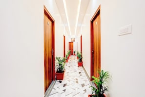A hotel hallway with wooden doors, potted plants, and a patterned floor. - Hotel O Virat Inn (Lucknow)