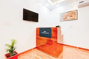 A reception area with a reception desk labeled 'YO TOWNHOUSE,' a mounted television, and a framed painting on the wall. - Hotel O Virat Inn (Lucknow)