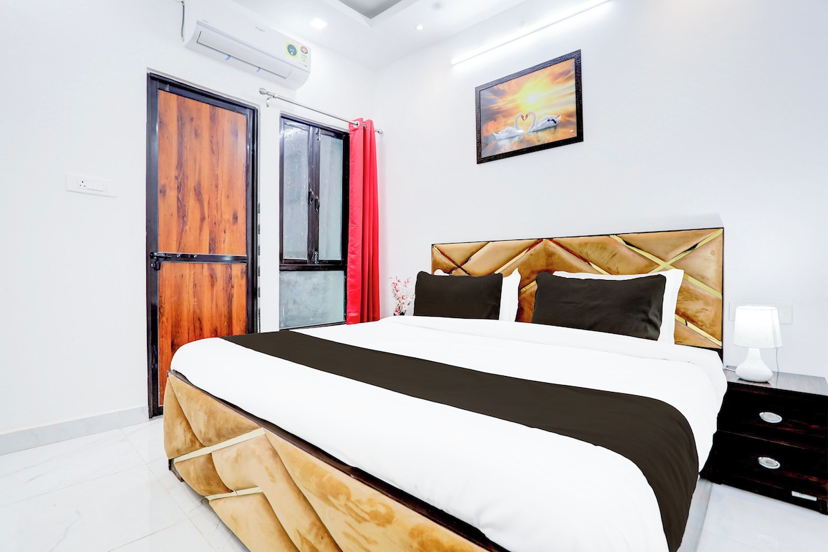 A modern bedroom with a large bed, a wooden wardrobe, a red curtain, and a painting on the wall.