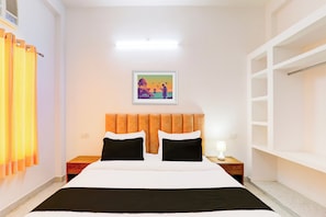 Ein Hotelzimmer mit Bett, Nachttisch, Lampe, einem Wandbild und einem Kleiderschrank.