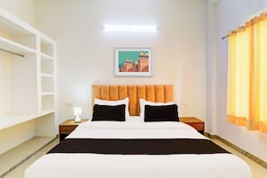 Habitación de hotel con cama, mesita de noche, lámpara, un cuadro en la pared y ventana con cortinas.