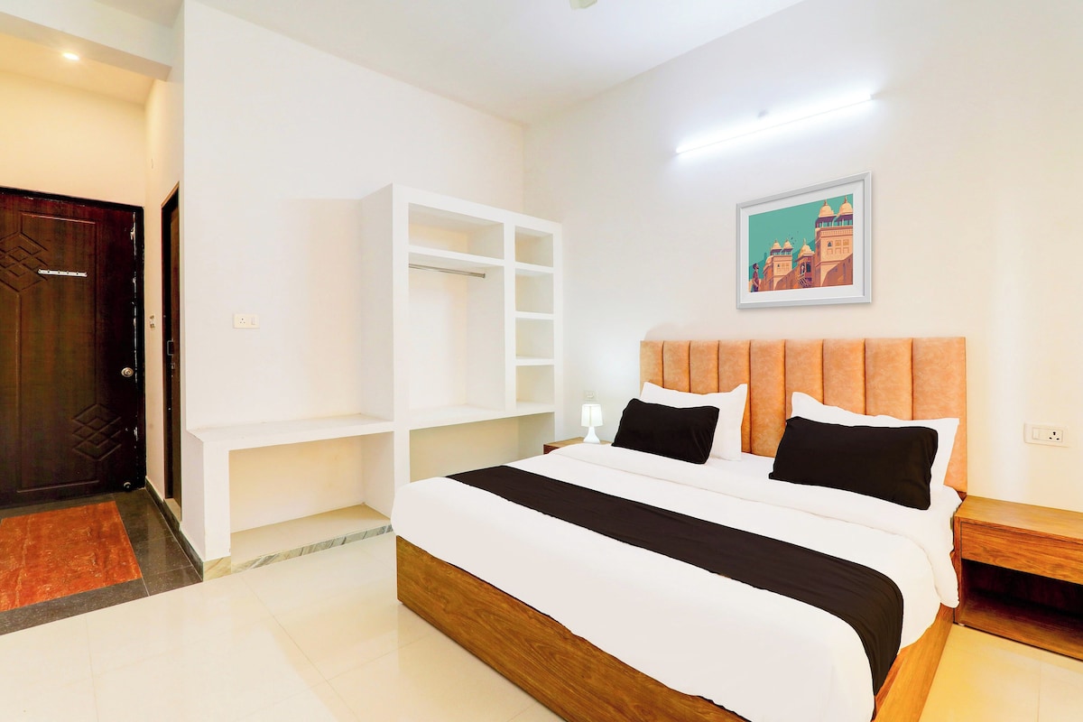 Een hotelkamer met een groot bed, een kast, een nachtkastje en een schilderij aan de muur.