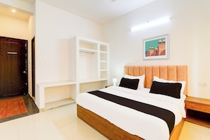 Una habitación de hotel con una cama grande, un armario, una mesita de noche y un cuadro en la pared.