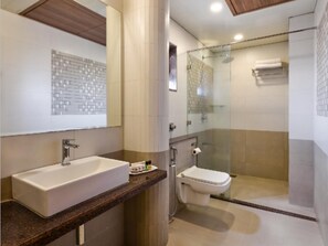 A bathroom with a sink, toilet, and glass-enclosed shower. - Raga Inn Sasan Gir (Sasan Gir)