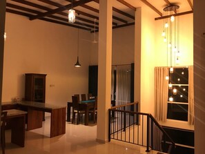 Un comedor con mesa y sillas de madera, un área de cocina con armarios y una escalera con barandilla.