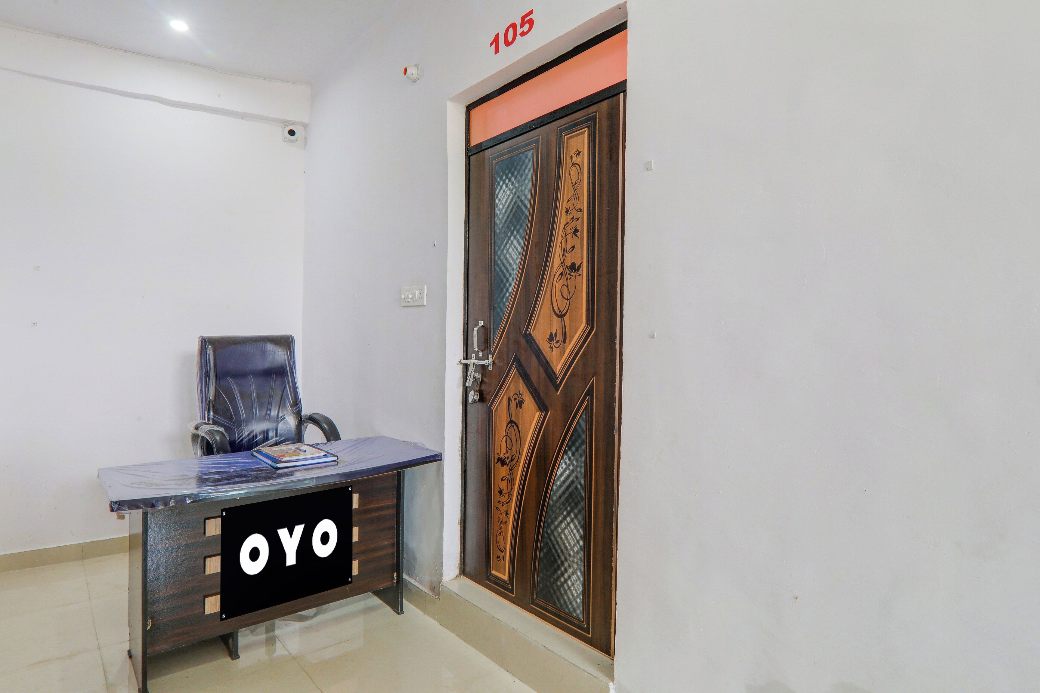 Een kamer met een houten deur, een bureau met een stoel en een bordje met 'OYO' erop.